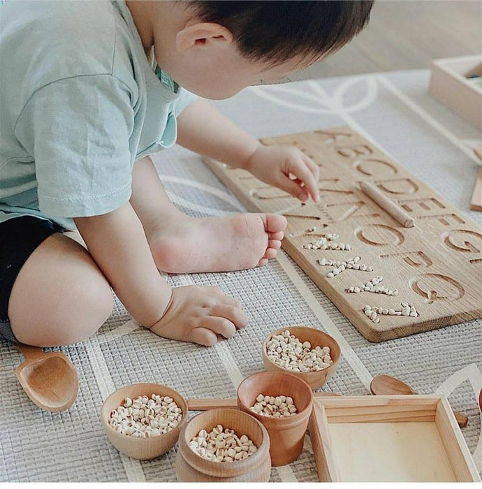 toddler using wooden alphabet tracing board